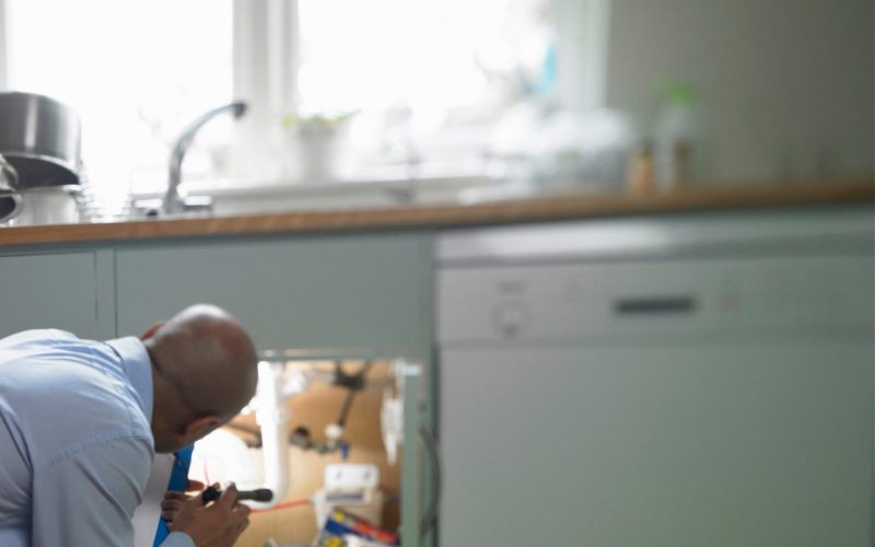 Man repairing plumbing under sink